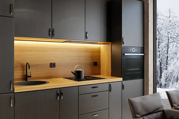Close-up of a compact, modern kitchen ideal for small apartments, vacation homes, or cabins. The cabinetry features dark wood tones such as walnut or deep oak, with a subtle, light texture that adds warmth and elegance. The modern black sink, faucet, and built-in oven remain integrated, while the standout feature is the stylish counter-top and back-splash, designed as bold accents against the rich cabinetry. The layout includes five key elements and a sleek hood positioned above the cooking surface, making it a functional and visually appealing choice for minimalist interiors and efficient spaces. Ideal for promoting modern material use, kitchen design, and small-space planning.
